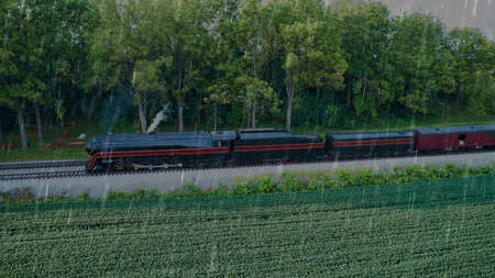 Aerial View of a Restored Antique Steam Engine Blowing Smoke and Steam in the Rain