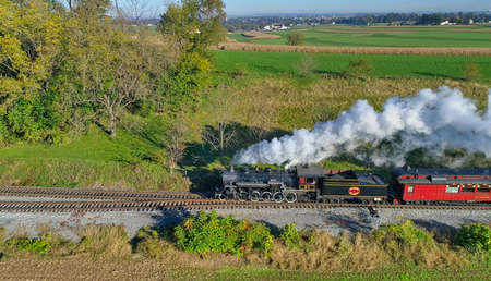 Strasburg, Pennsylvania, October 2020 - Aerial View of Steam Passenger Train Puffing Smoke Traveling...