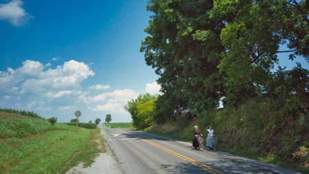 Ronks, Pennsylvania, July 2020 - 2 Amish Women Riding Scooters on a Road on a Summer Dayのeditorial素材