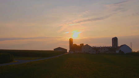 View of a Sunrise Looking over an Amish Farm with Farm House Barn and Silosの写真素材