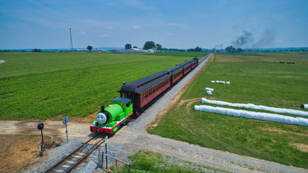 Ronks, Pennsylvania,June 2019 - Aerial View of Percy the Tank Engine Approaching Thru Trees and Farmlands Pulling Passenger Cars Blowing Smoke on a Beautiful Summer Dayのeditorial素材