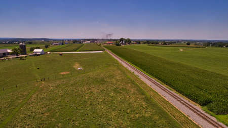 Aerial View of a Steam Locomotive Traveling Across a Fertile Farmland Landscape on a Beautiful Summer Dayの写真素材