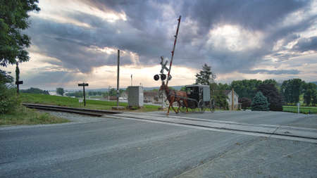 An Amish Horse and Buggy Crossing a Rail Road Crossing on a Dramatic Summer Day