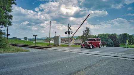 Ronks, Pennsylvania, June 2021 - An Antique Car With a horse and Buggy Behind it Waiting at a Rail Road Crossing on a Sunny Dayのeditorial素材