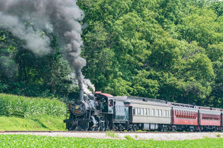 View of an Antique Restored Steam Passenger Train Blowing Smoke and Steam on a Sunny Summer Dayの写真素材