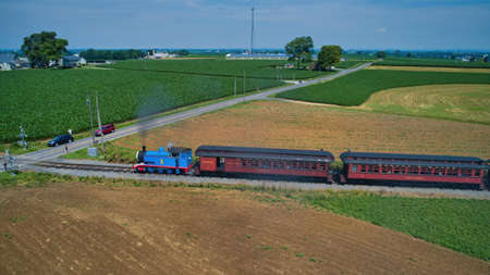 Ronks, Pennsylvania,June 2019 - Aerial View of Thomas the Tank Engine Approaching Thru Trees and Farmlands Pulling Passenger Cars Blowing Smoke on a Beautiful Summer Dayのeditorial素材