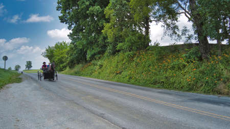 Ronks, Pennsylvania, June 2021 - Amish Open Horse and Buggy Approaching With a Couple and Daughter in it on a sunny Dayのeditorial素材