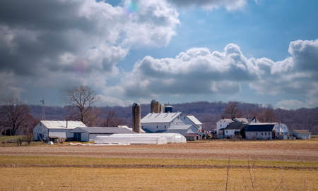 View of a Farm Homestead With Barns, Silos, Farm House and Other Buildings on a Partly Cloudy Dayの写真素材