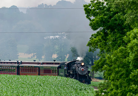 Ronks, Pennsylvania, June 18, 2021 - View of a Restored Steam Passenger Train Approaching Around a Curve With Smoke and Steamのeditorial素材