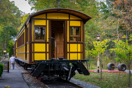 Elizabethtown, Pennsylvania, October 7, 2020 - Installing a New Yellow Passenger Antique Coach Being Lifted By a Crane to install on Train Trucks on to a Railroad Track on a Fall Dayのeditorial素材