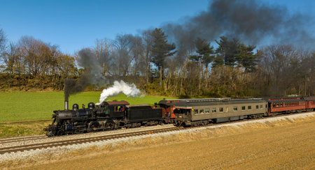 A Drone View of a Restored Steam Passenger Train Traveling Thru Farmlands Pulling Up to a Small...