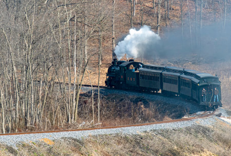 Shirleysburg, Pennsylvania, February 19, 2023 - View of a Narrow Gauge Restored Steam Passenger Train Blowing Smoke and Traveling Thru Farmlands on a Winter Dayのeditorial素材