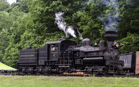 Cass, West Virginia, June 18, 2022 - An Antique Shay Steam Engine, Traveling by Itself, Blowing Smoke and Steam on a Rail Road Track, on a Summer Dayのeditorial素材