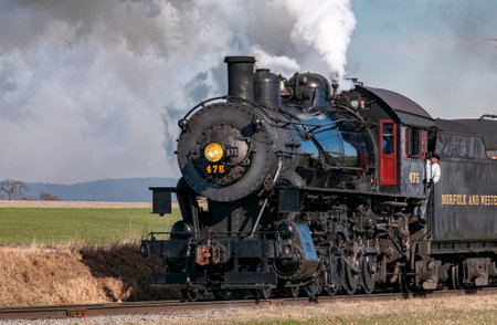 Ronks, Pennsylvania, December 28, 2022 - A View of a Classic Steam Passenger Train Approaching, Traveling Thru the Countryside, Blowing Smoke and Steam on a Winter Dayのeditorial素材