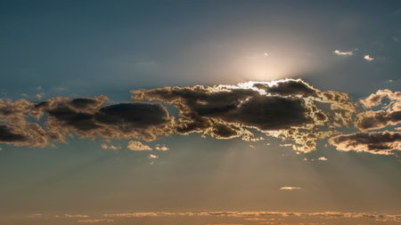 A View of the Late Afternoon Sun Playing Peek a Boo with Clouds on a Summer Dayの写真素材