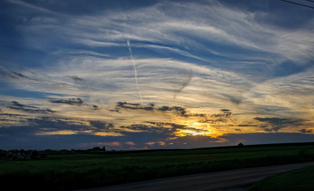 A View of a Sunset Over Farmlands With a Blue Sky and Golden Clouds, on a Summer Dayの写真素材