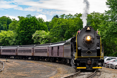 A View of A Restored Steam Passenger Train Approaching Around a Curve Traveling Thru Rural America on a Sunny Dayの写真素材