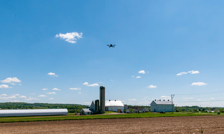 A View of Farmlands With Barns, Silos, and s Drone Flying on a Sunny Dayの写真素材