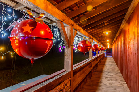 A View of a Covered Bridge Decorated for Christmas With Lights and Large Ornamentsの写真素材