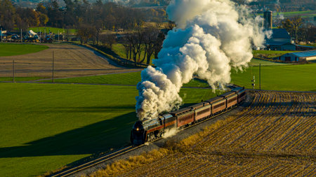 An Aerial View at Sunrise of a Steam Passenger Train Approaching Blowing A Lot of Smoke on a Autumn Dayのeditorial素材