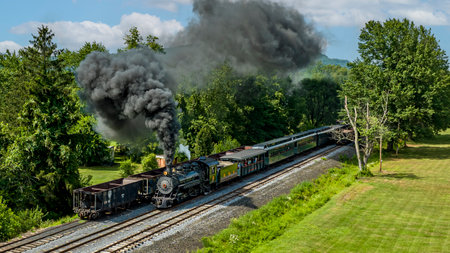 Rockhill Furnace, Pennsylvania, August 5, 2023 - An Aerial View of a Narrow Gauge Steam Passenger Train, Approaching, Blowing Smoke, Passing Coal Hoppers, on a Sunny Summer Dayのeditorial素材