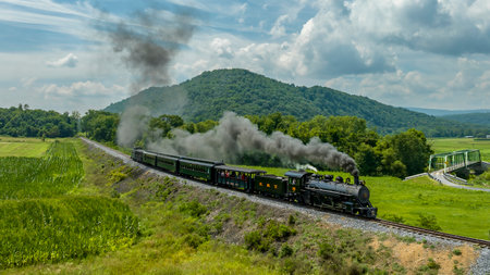 Rockhill Furnace, Pennsylvania, August 5, 2023 - An Aerial View of a Narrow Gauge Steam Passenger Train, Approaching Traveling Around a Curve Thru Countryside, Blowing Smoke, on a Sunny Summer Dayのeditorial素材