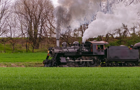 A Side and Slightly Ahead View of a Restored Steam Passenger Train Traveling By on a Cloudy Day