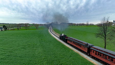 Captivating aerial photo of a historic steam train emitting a dense smoke plume as it winds through...