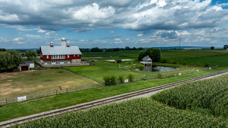 Ronks, Pennsylvania, August 15, 2023 - Dominating this pastoral scene is a classic red barn with a serene pond and gazebo, set against the rich tapestry of flourishing cornfields.のeditorial素材