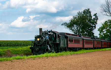 A Black Steam Locomotive Numbered 89, Pulling Red Passenger Cars With The Name Strasburg, Travels...