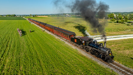 Ronks, Pennsylvania, USA, June 8, 2024 - A Vintage Steam Locomotive Pulling Red Passenger Cars...