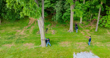 Ronks, Pennsylvania, USA, June 8, 2024 - Civil War Reenactors In Blue Uniforms Strategically Position Themselves Among Tall Trees In A Forested Area, Each Holding Rifles, Amidst Lush Green Foliage And Grass, Engaged In A Skirmish Scene.のeditorial素材