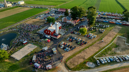 Ronks, Pennsylvania, USA, July 3, 2024 - Aerial View Of A Farm Hosting A Large Gathering With A Red Barn, Food Trucks, Parking Area, And Pond With Fountains.のeditorial素材