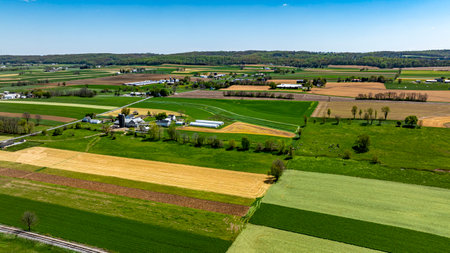 This captivating landscape showcases expansive farmland with a patchwork of green and brown fields