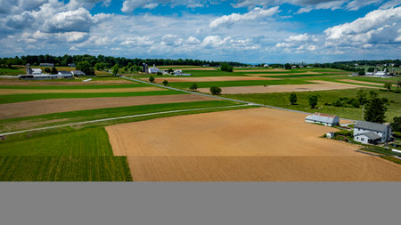 Vast agricultural fields dominate the landscape, showcasing a mix of green crops and brown earth.の写真素材