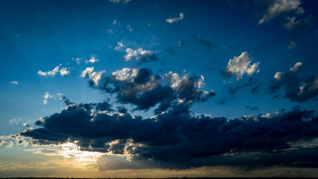 A stunning display of colors fills the sky as the sun sets, casting shadows on the clouds and creating a tranquil atmosphere during the evening hours.の写真素材