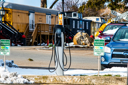 A charging station for electric vehicles is positioned in a snowy parking lot, surrounded by...