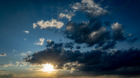 A stunning display of colors fills the sky as the sun sets, casting shadows on the clouds and creating a tranquil atmosphere during the evening hours.の写真素材