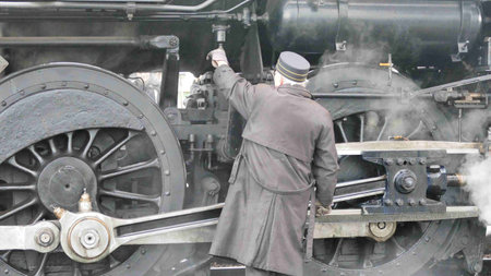 A steam engineer works diligently on the machinery of a vintage locomotive, ensuring its readiness for travel. The Strasburg, Pennsylvania, December 31, 2024 - scene captures the essence of railway history in the winter.の写真素材