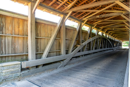 Visitors walk through the interior of a historic covered bridge, admiring its intricate wooden...