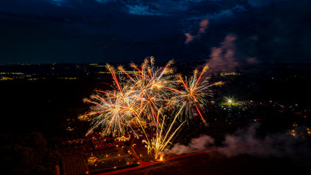 A spectacular display of fireworks lights up the night sky above a park, celebrating a community event with families and friends gathered below.の写真素材