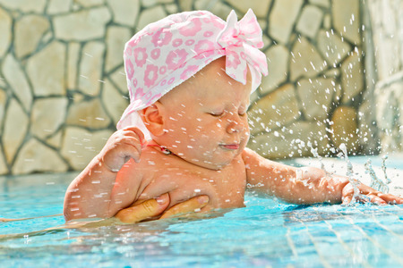 girl claps her palms on the water in the swimming poolの写真素材