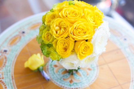 bridal bouquet and boutonniere of yellow, green and white roses arranged gradient on the tableの写真素材