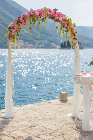 pink wedding arch of peons and hydrangea with a sea viewの写真素材