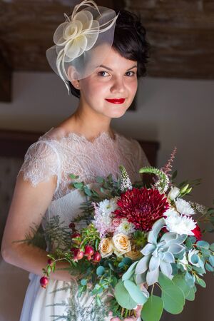 Portrait of the bride with brightly lipstick which holds a bouquetの写真素材