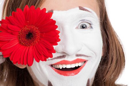 mime actor smiles attaching to face red flowerの写真素材
