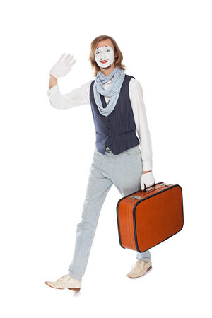 actor mime waves his hand walking with orange suitcaseの写真素材