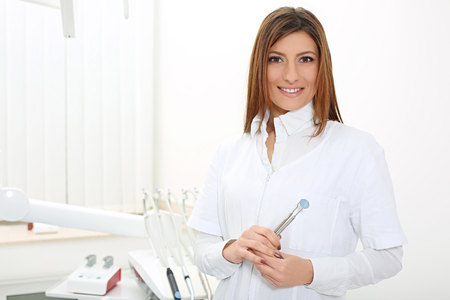 beautiful girl dentist smiling and holding a mirror and dental probeの写真素材