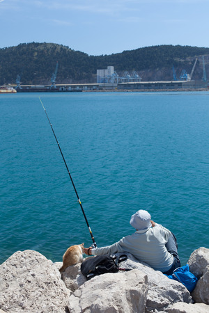 fisherman fishes in the company of a catの写真素材
