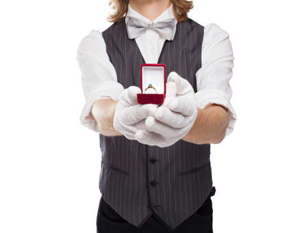 man in a bow tie holds out forward open box with the ringの写真素材
